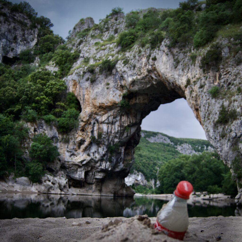 Vallon pont d'arc, l'arche naturelle. Un cadavre de bouteille de coca au premier plan.